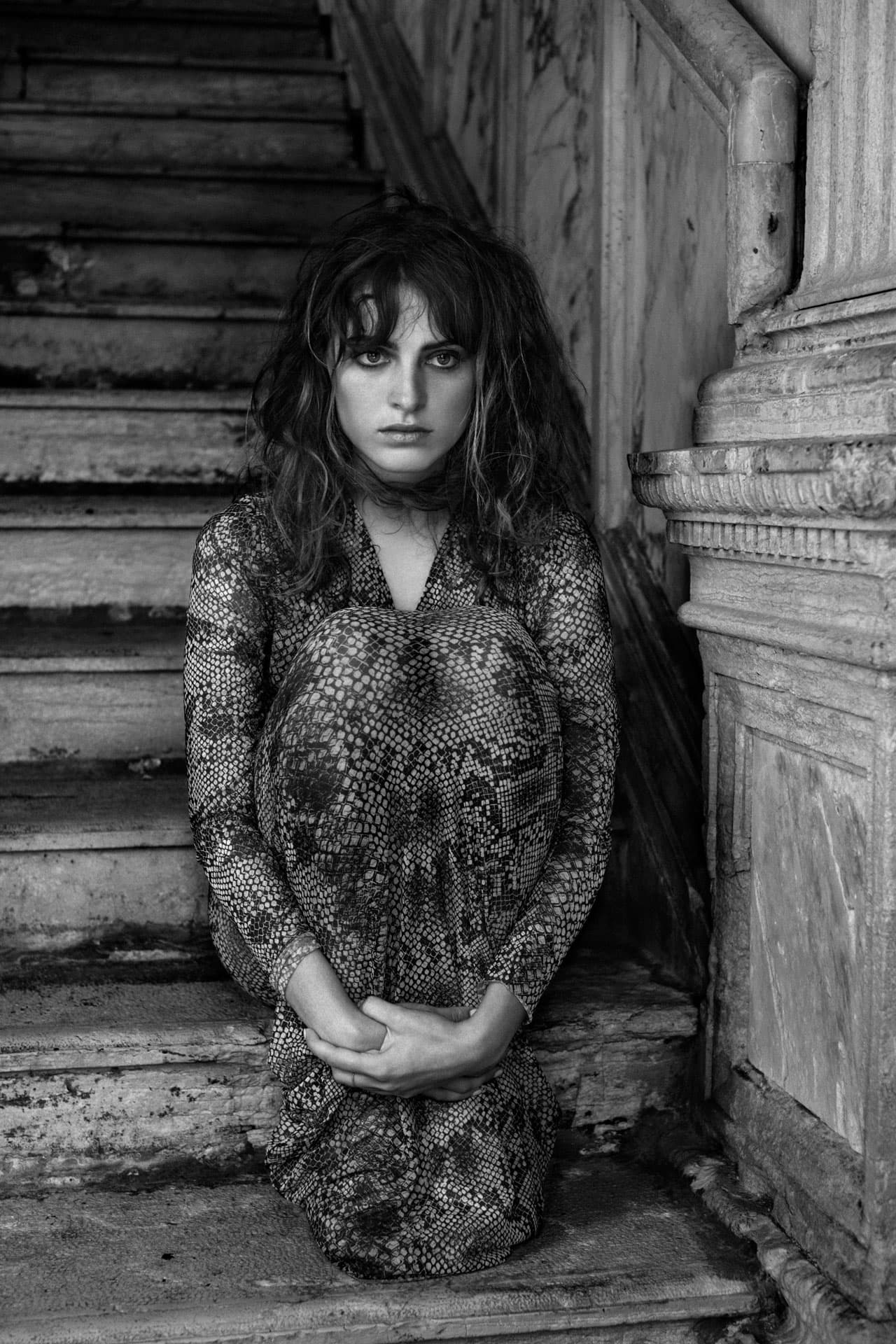 Jeune femme au regard nostalgique assise sur les marches d'un palais à Venise.