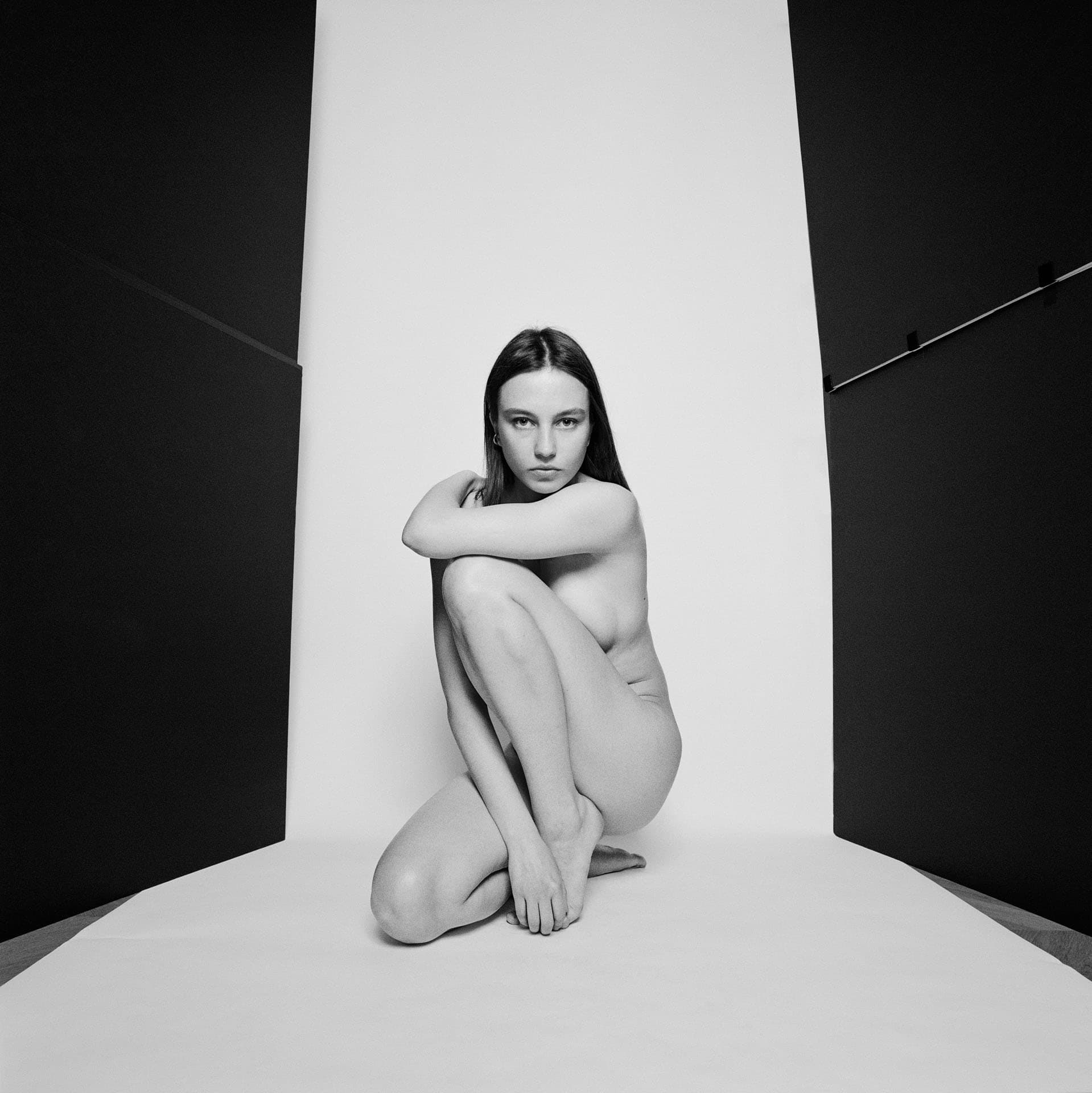 Étude de nu féminin en studio sur fond blanc.