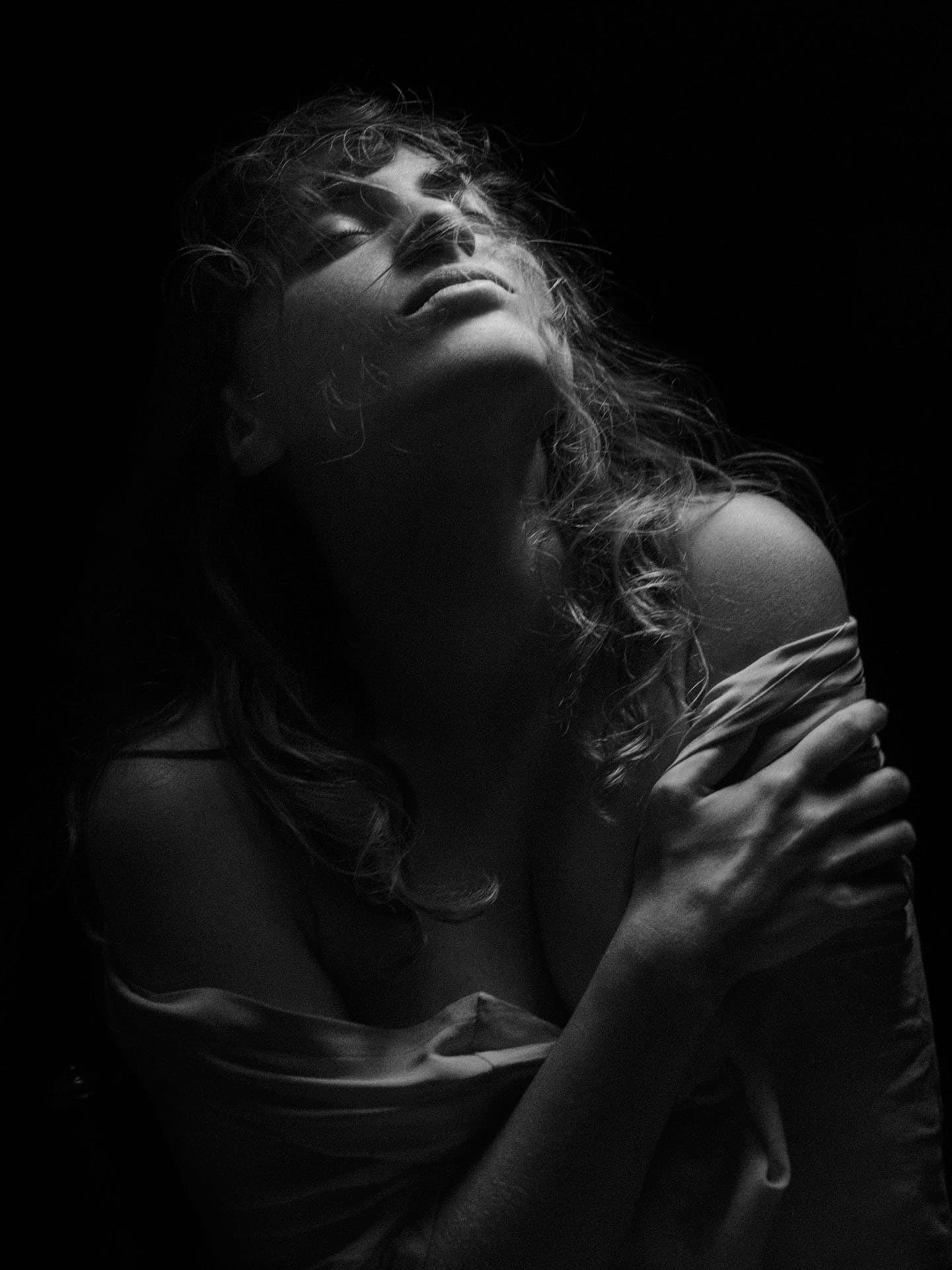 Portrait en studio d'une jeune femme se saisissant le bras gauche.