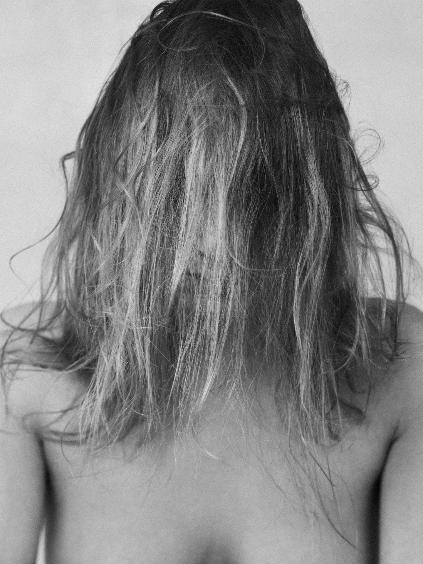 Jeune femme se cachant le visage derrière ses fins cheveux blonds.