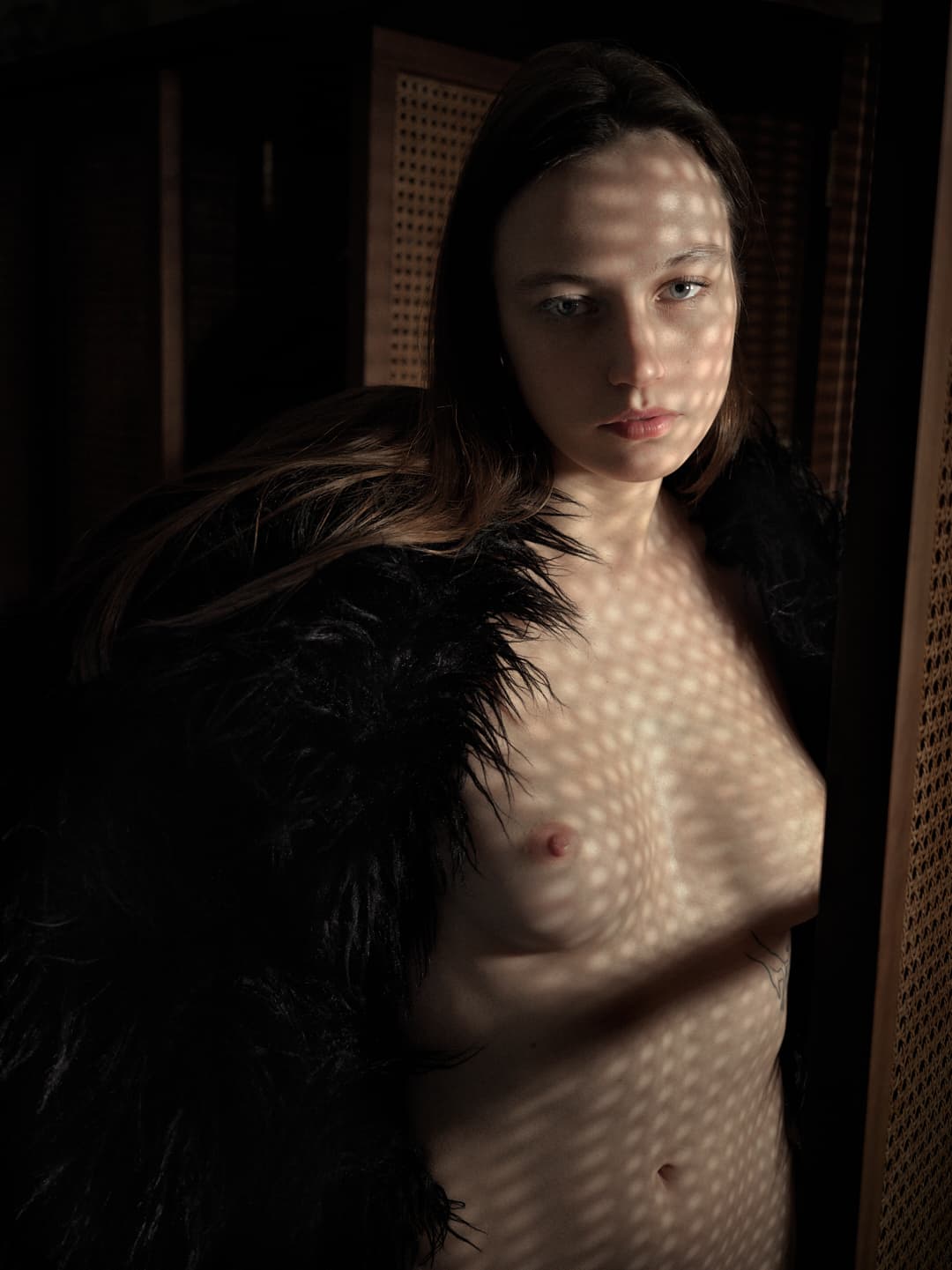 Portrait de nu avec un motif géométrique d'ombre projeté sur le visage et le corps de la modèle.