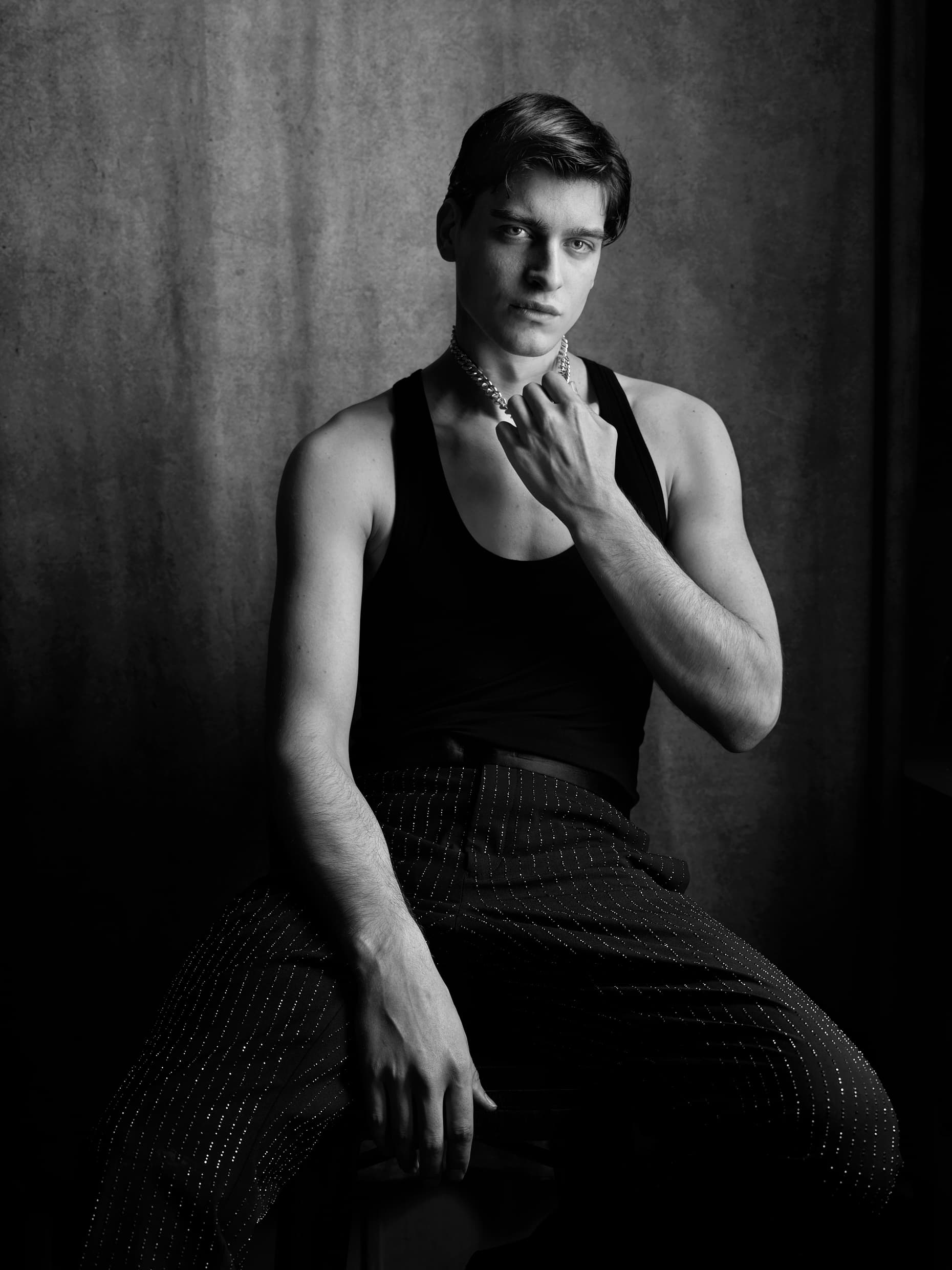Portrait en noir et blanc d'un modèle masculin assis, éclairage sculptural.
